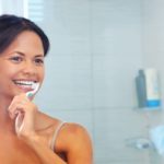 A women following our tips on how to prevent cavities by brushing teeth