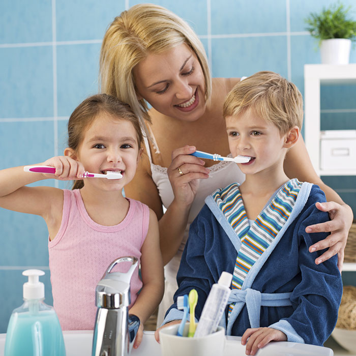 A mom brushing teeth with her two children