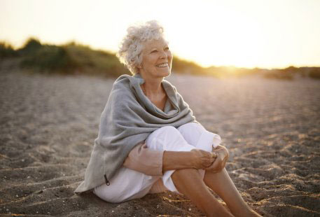 A mature woman sitting on sand at the beach