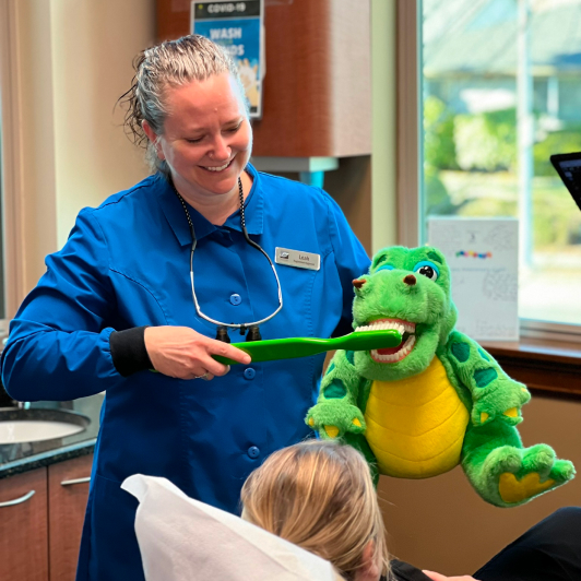 Leah, our Dental Hygienist, demonstrating the brushing process on a plushie